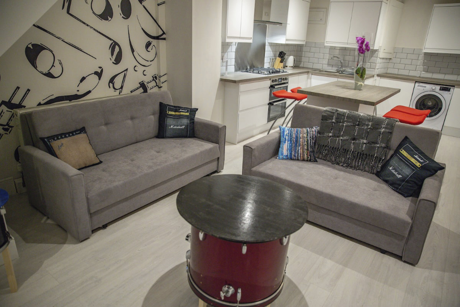 An open plan kitchen, diner and living area featuring a coffee table made from a repurposed drum and music themed feature wall