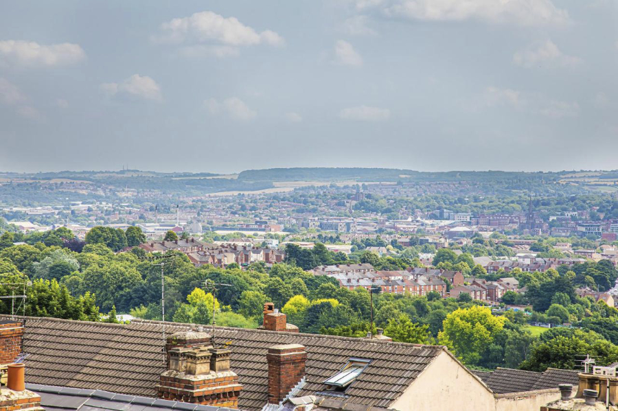 The view from a new loft conversion, showing diverse houses and trees across the city of Sheffield, with hills in the distance