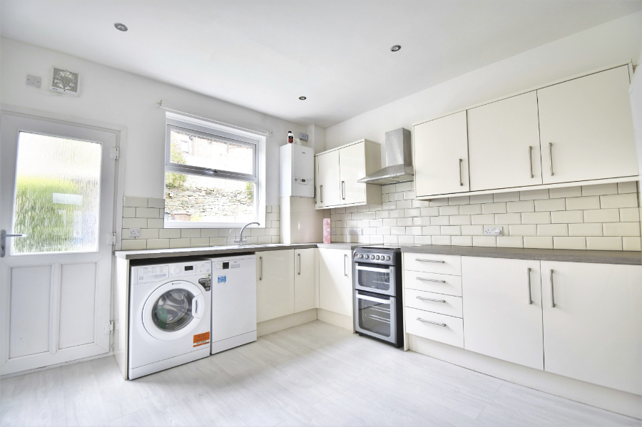 A newly refurbished modern kitchen with cream units and metro tiles, wooden worktops, new appliances and laminate flooring